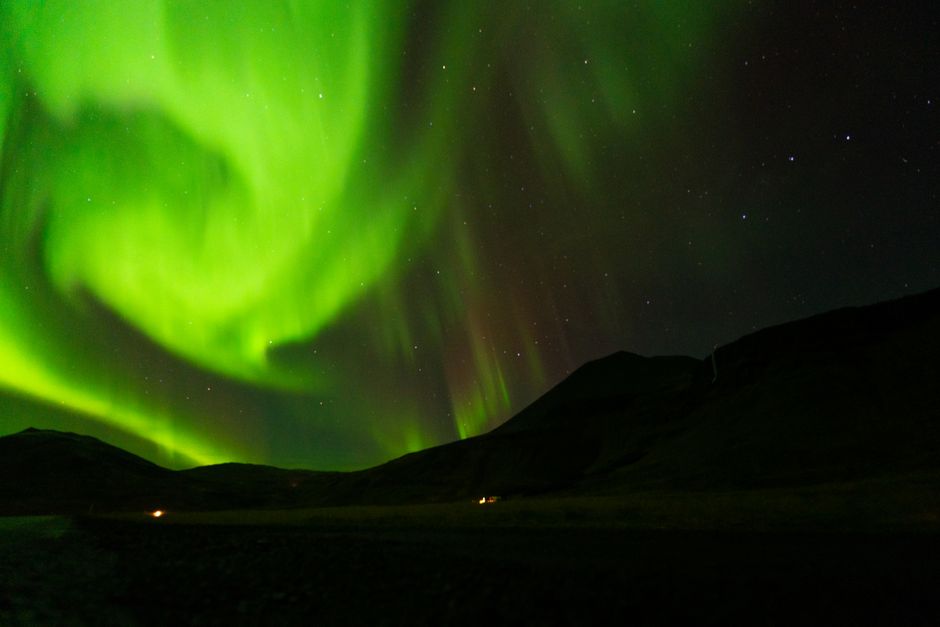 Breathtaking display of the aurora borealis illuminating a mountain range under a starry night sky.