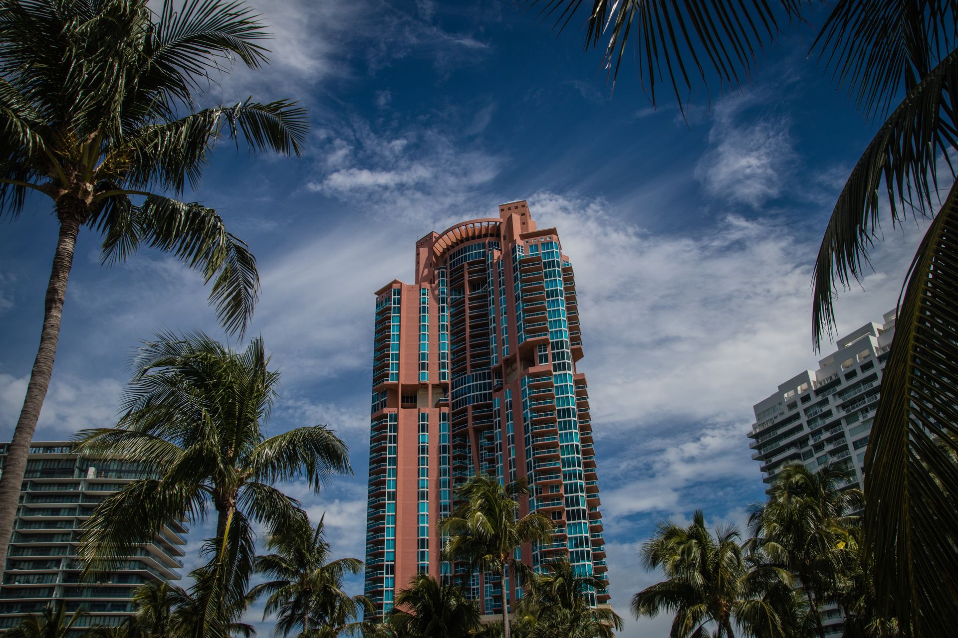 Miami Beach high-rise hotel tower framed by palm trees under a blue sky