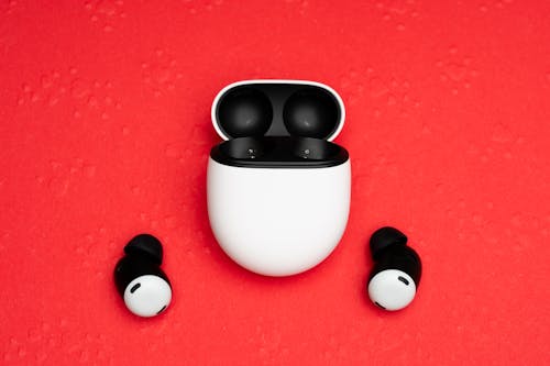 An image of a pair of airpods on a red surface