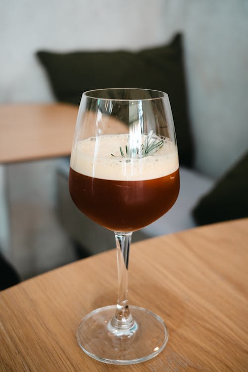 A glass of coffee on a table with a rosemary sprig