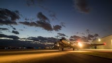 暮色渐临，一架老式飞机停在跑道上，光影交织