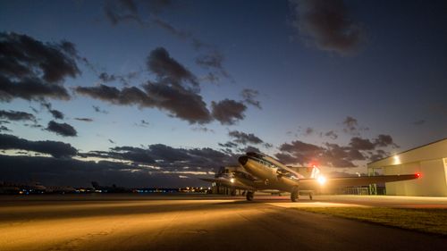 Free A vintage aircraft sits on the runway as the sky transitions to twilight, blending light and shadow. Stock Photo