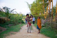 孩子们在阳光明媚的一天，快乐地走在乡村小径上，周围是郁郁葱葱的绿色植物