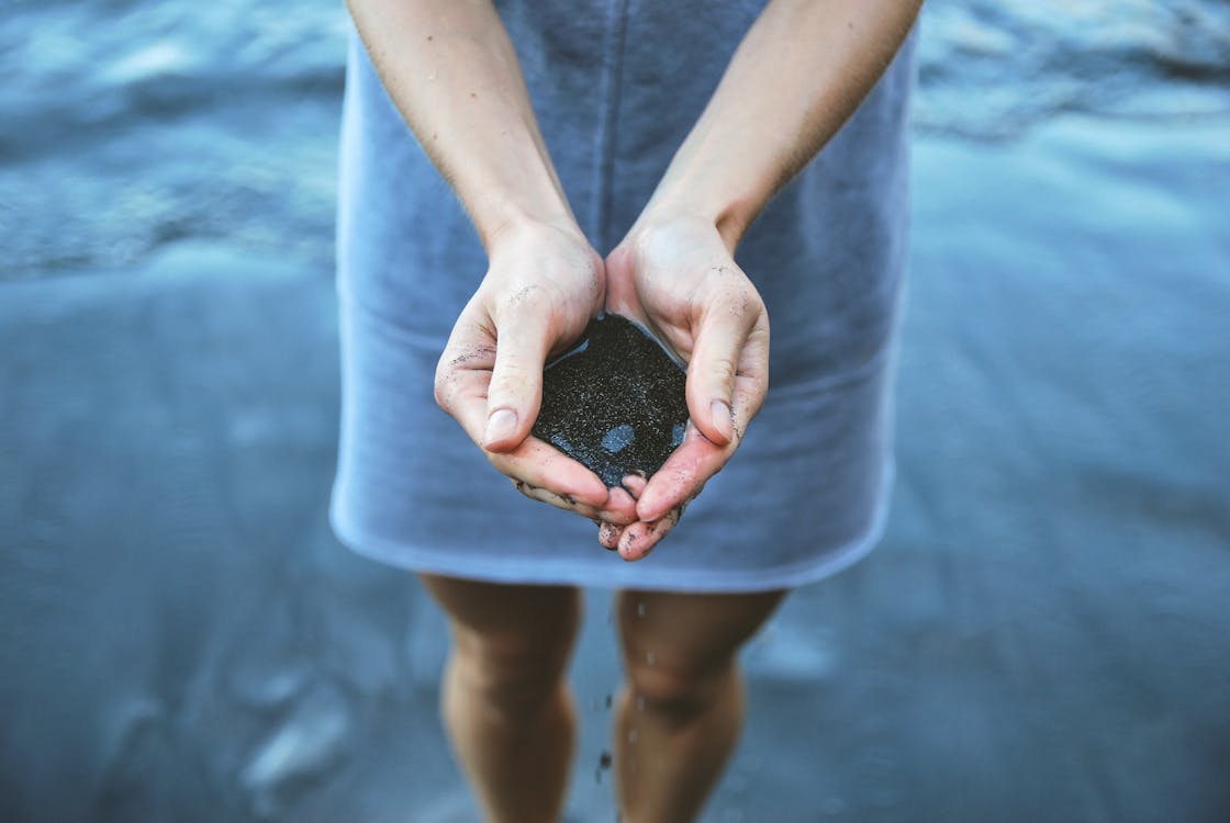 無料 海岸デュで黒砂を保持している女性 写真素材
