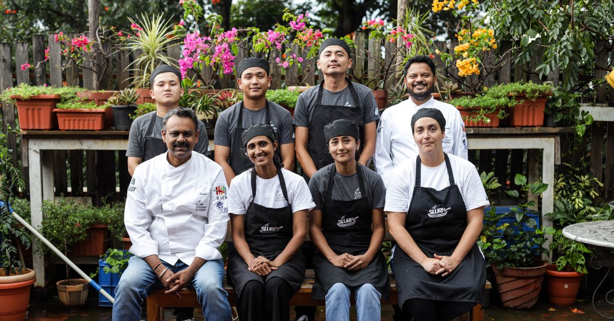 Team of chefs and kitchen staff smiling in a vibrant garden, showcasing unity and professionalism.