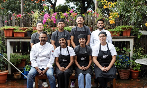 Team of chefs and kitchen staff smiling in a vibrant garden, showcasing unity and professionalism.