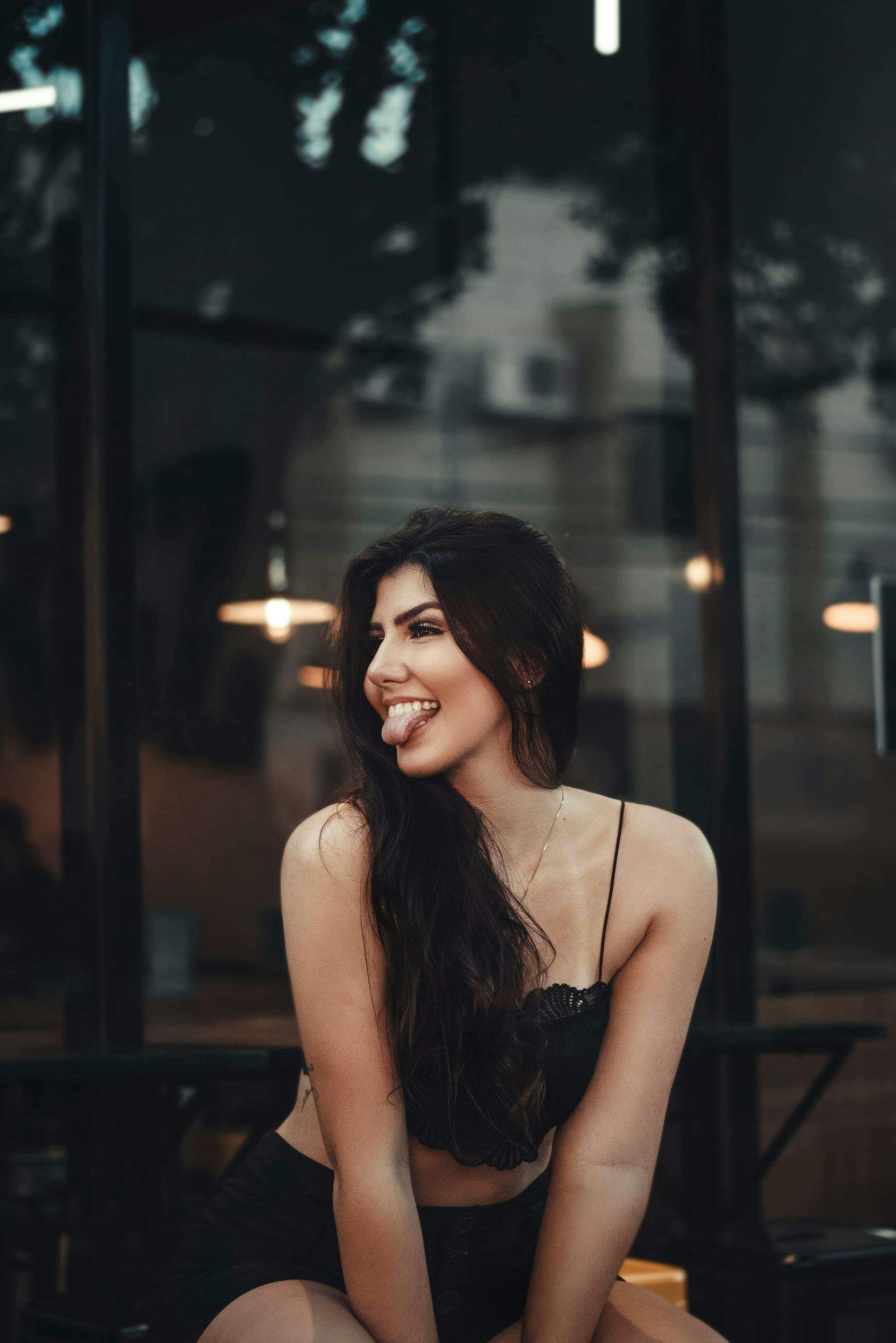 woman sitting by the glass window sticking out tongue