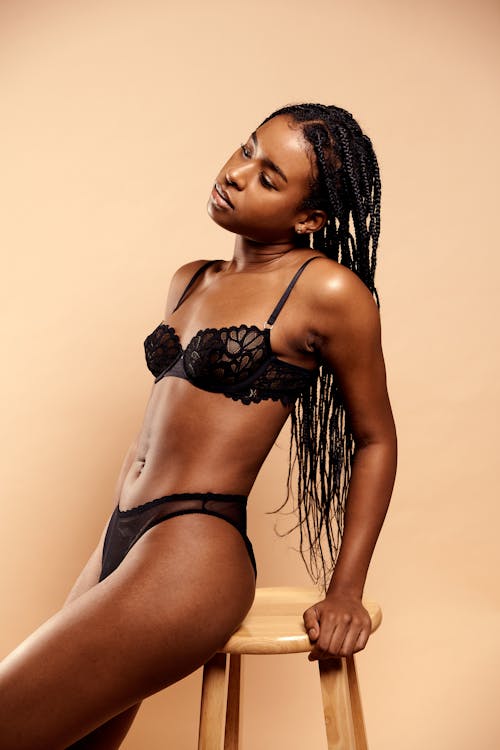 A black woman in lingerie sitting on a stool