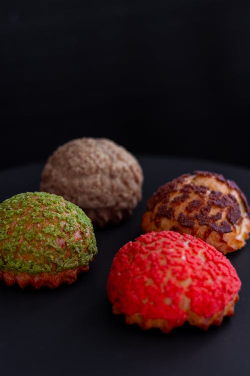 Four different colored pastries on a black surface