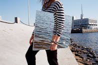 女人通过镜子反射大海，在城市滨水区营造出独特的水景效果