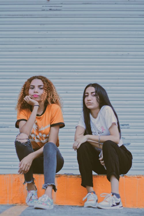 オレンジ色のコンクリートの経路に座っている2人の女性