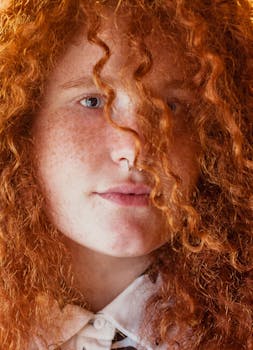 一位女性特写肖像，她有着充满活力的红色卷发和雀斑，戴着隔膜环