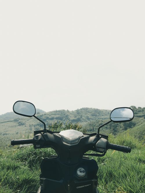 Free Moped in a lush Indonesian countryside, framed by rolling hills and misty sky. Stock Photo