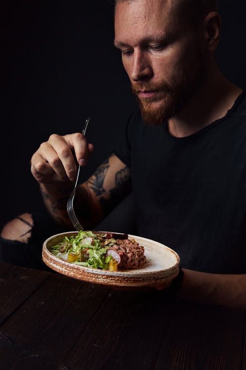 Free Man Eating Meat with Vegetables Stock Photo