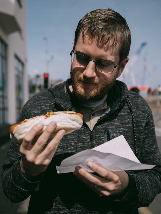 A man eating a hot dog while holding a paper