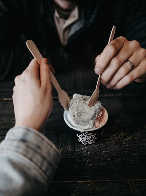 A person holding a spoon and eating ice cream