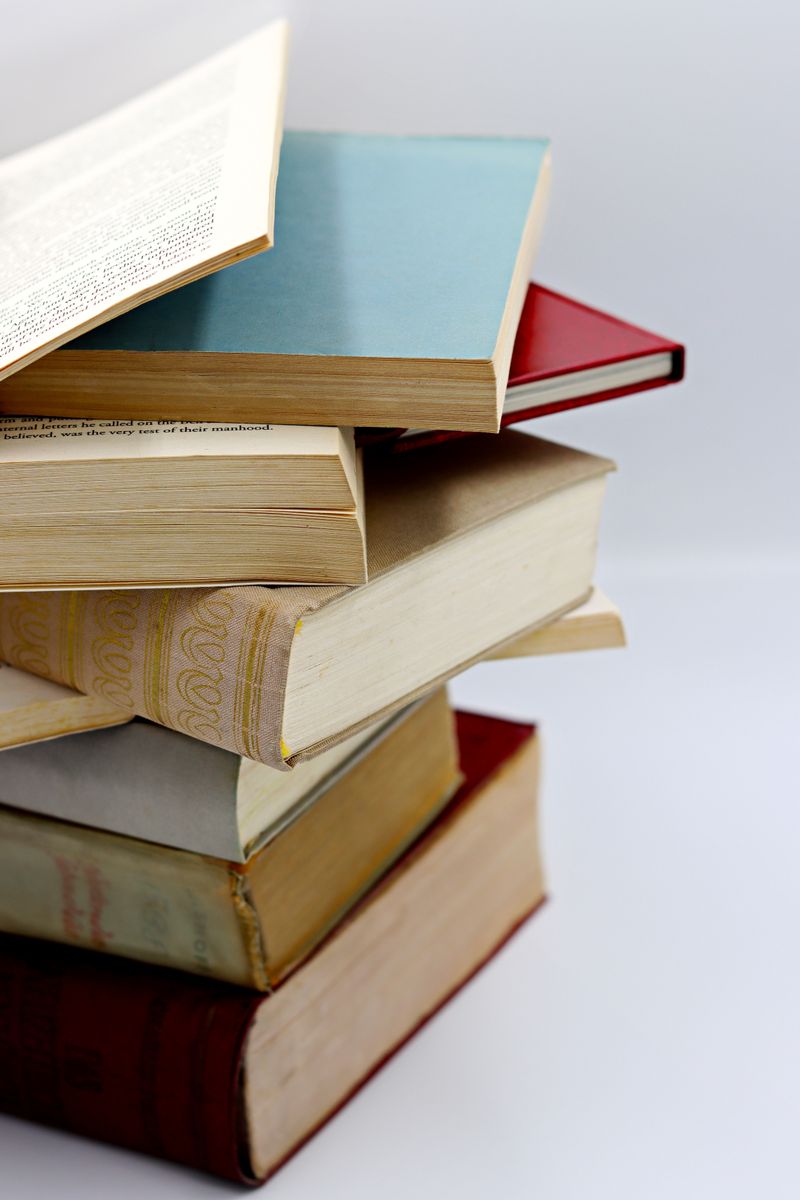 A vertical stack of various hardcover books with visible pages, ideal for literature themes. A vertical stack of various hardcover books with visible pages, ideal for literature themes.