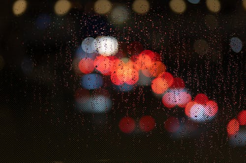 A blurry image of cars and lights through a rain covered window