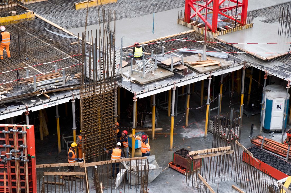 Workers in high visibility gear erecting a steel frame on a construction site