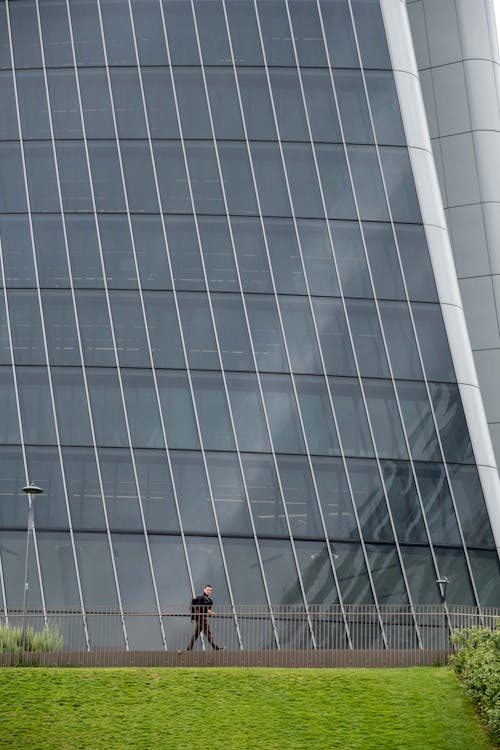 Man Near a Metal Fence and a High Rise Building