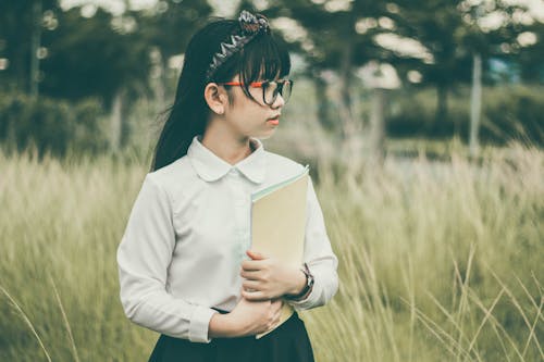 Chica En Camisa Blanca De Manga Larga Y Pantalones Negros Con Carpeta Marrón