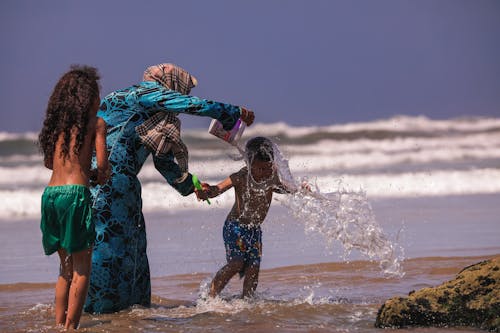 Free Woman and Two Boys on Shore Stock Photo