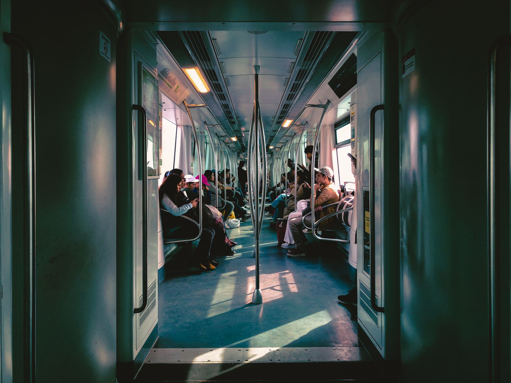 Inside view of a metro train in Lima, Peru, with passengers engaged in activities.