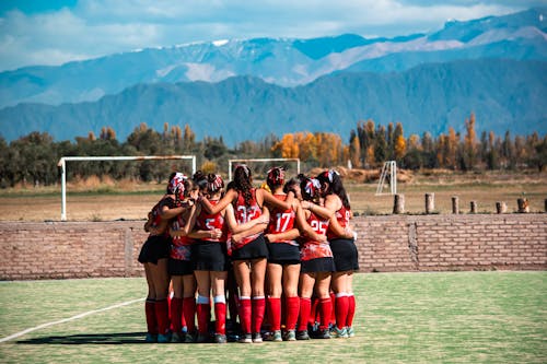 A group of girls in red and black uniforms huddle together