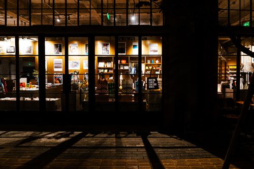 Free A night-time view of a retail store window showcasing bags and posters, creating a warm urban atmosphere. Stock Photo