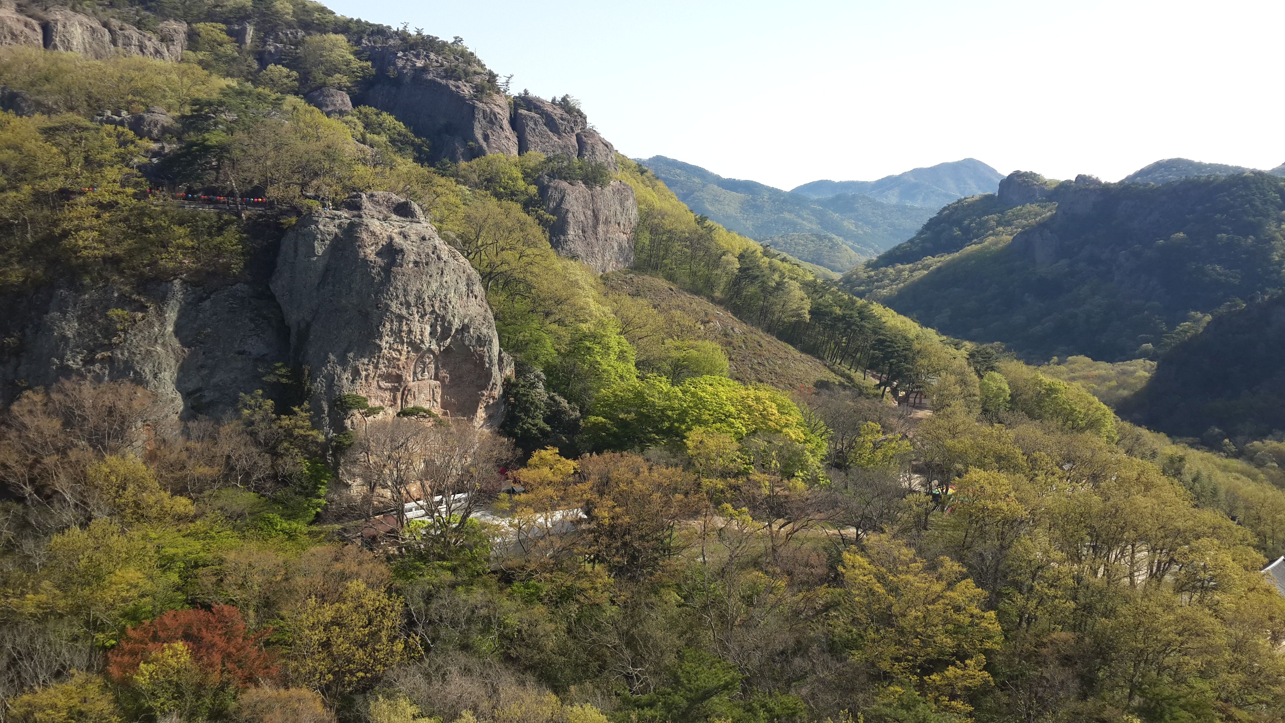 맑은 파란 하늘 아래, 울창한 녹색 산, 절벽 및 나무의 숨막히는 항공 전망.