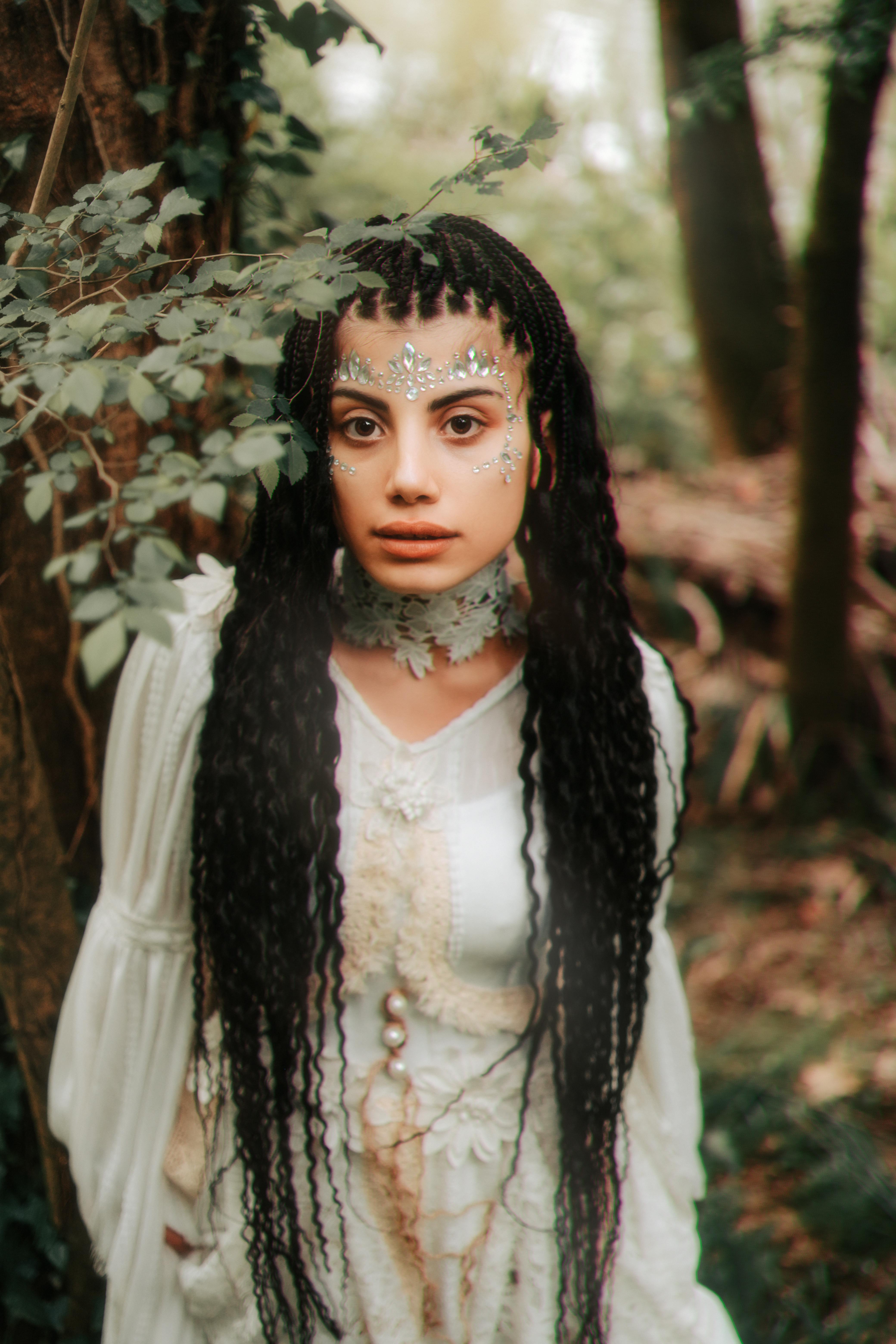 Stunning portrait of a woman in a fairy-inspired costume posing in a lush forest.