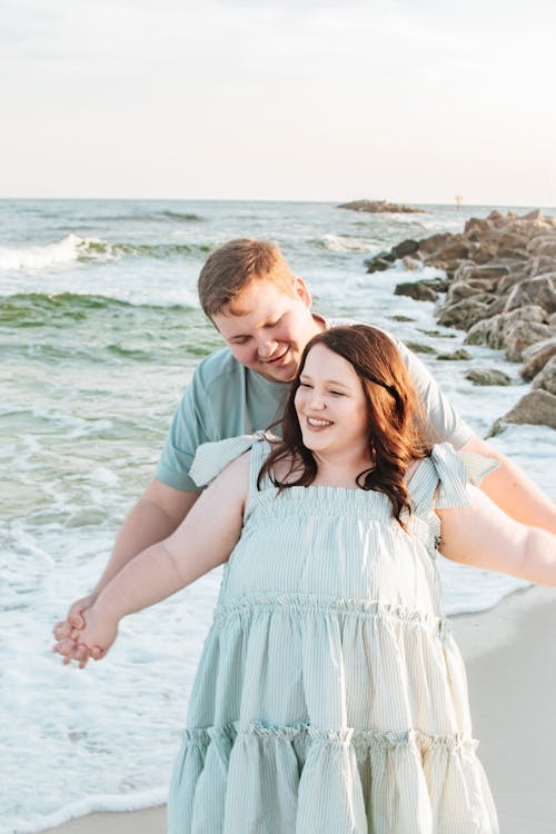 A couple holding hands on the beach during their engagement session