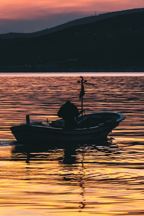 A man in a small boat at sunset