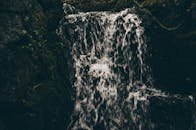 在幽暗而茂密的森林中，一道宁静的瀑布从长满青苔的岩石上倾泻而下