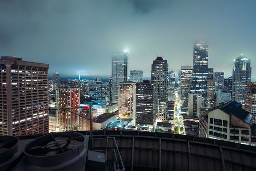 Stunning aerial view of Seattle's illuminated skyline with fog and modern skyscrapers at night.