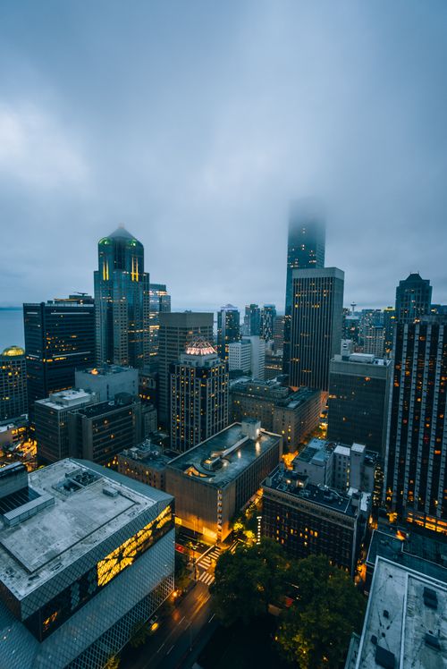 Free Captivating aerial twilight view of fog-covered Seattle skyline with illuminated skyscrapers and modern architecture. Stock Photo
