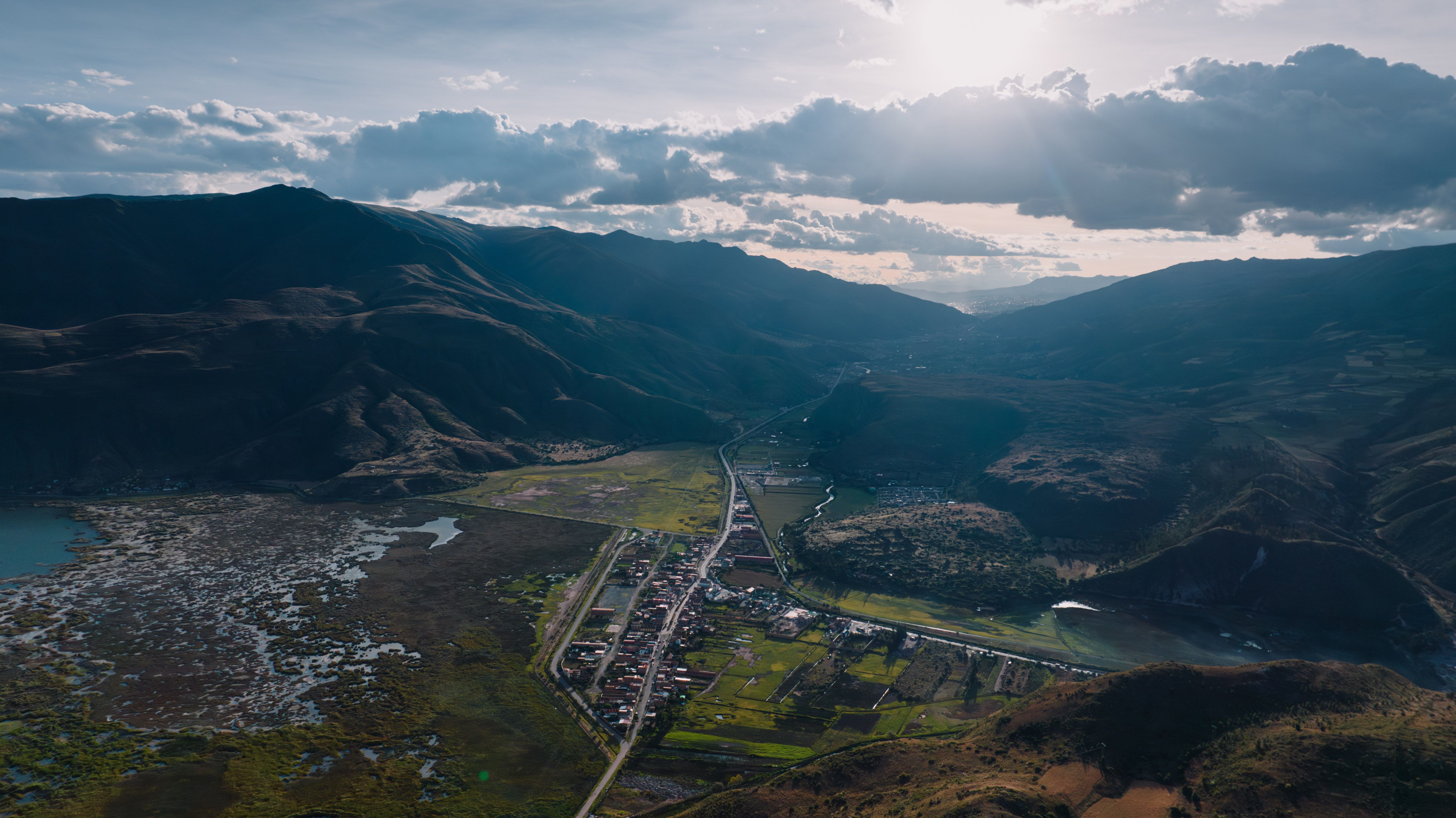 Breathtaking aerial view of the Cusco valley showcasing mountains and a serene village.