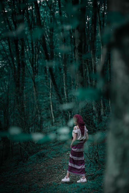 Woman Wearing Maroon and White Striped Skirt Standing on Green Grass