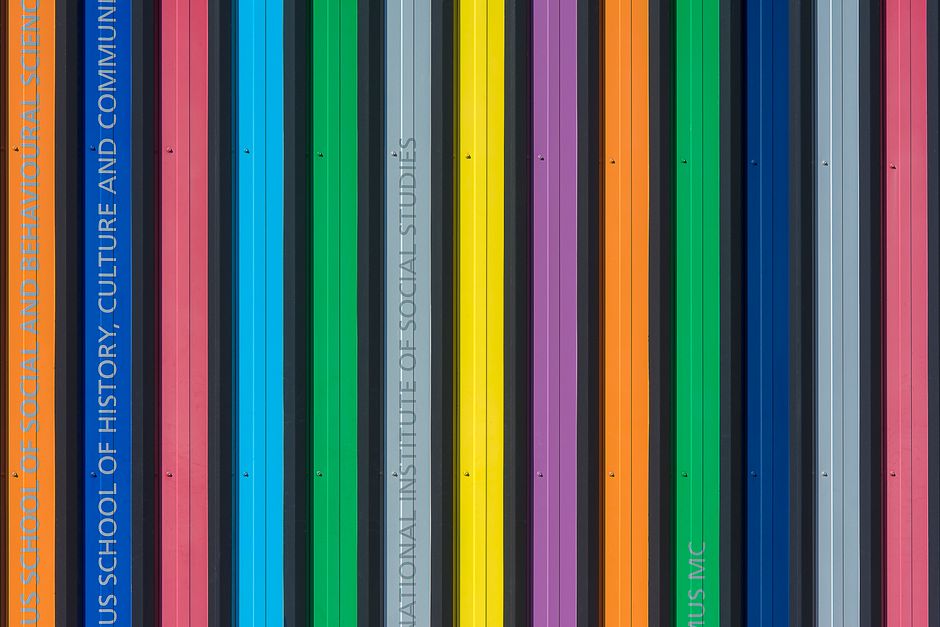 Vibrant multi-colored vertical stripes on a modern building facade, showcasing bold architectural design.