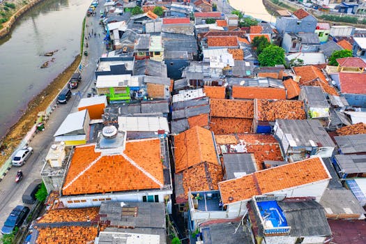 航拍照片中，蜿蜒的河流旁，茂密的村庄屋顶清晰可见