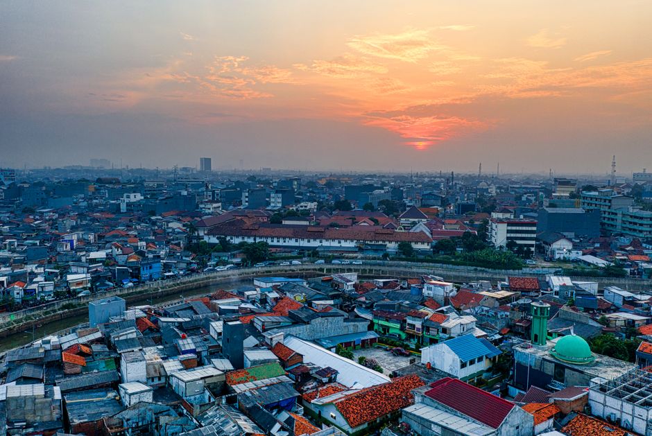 A stunning aerial view of an urban cityscape at sunset with vibrant skies and dense housing.