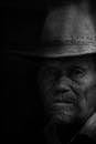一位老人戴着牛仔帽的黑白肖像，充满戏剧性
