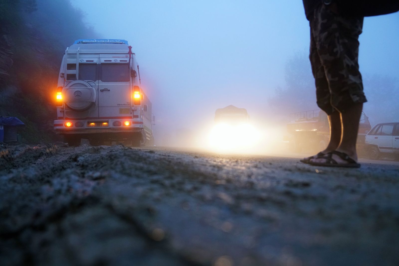 Rural road in freezing fog with a bright white fog line along the right edge guiding the driver