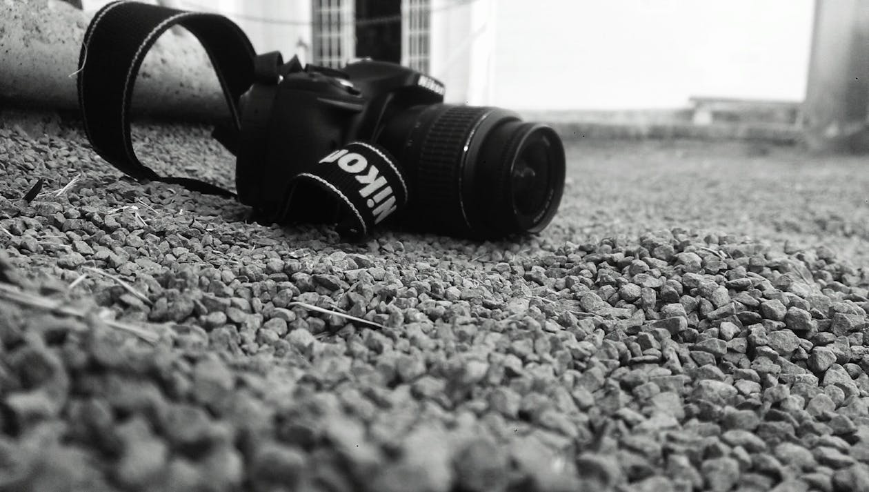 бесплатная фотоаппарат Nikon Dslr установлен на земле с обломками фото в оттенках серого Стоковое фото
