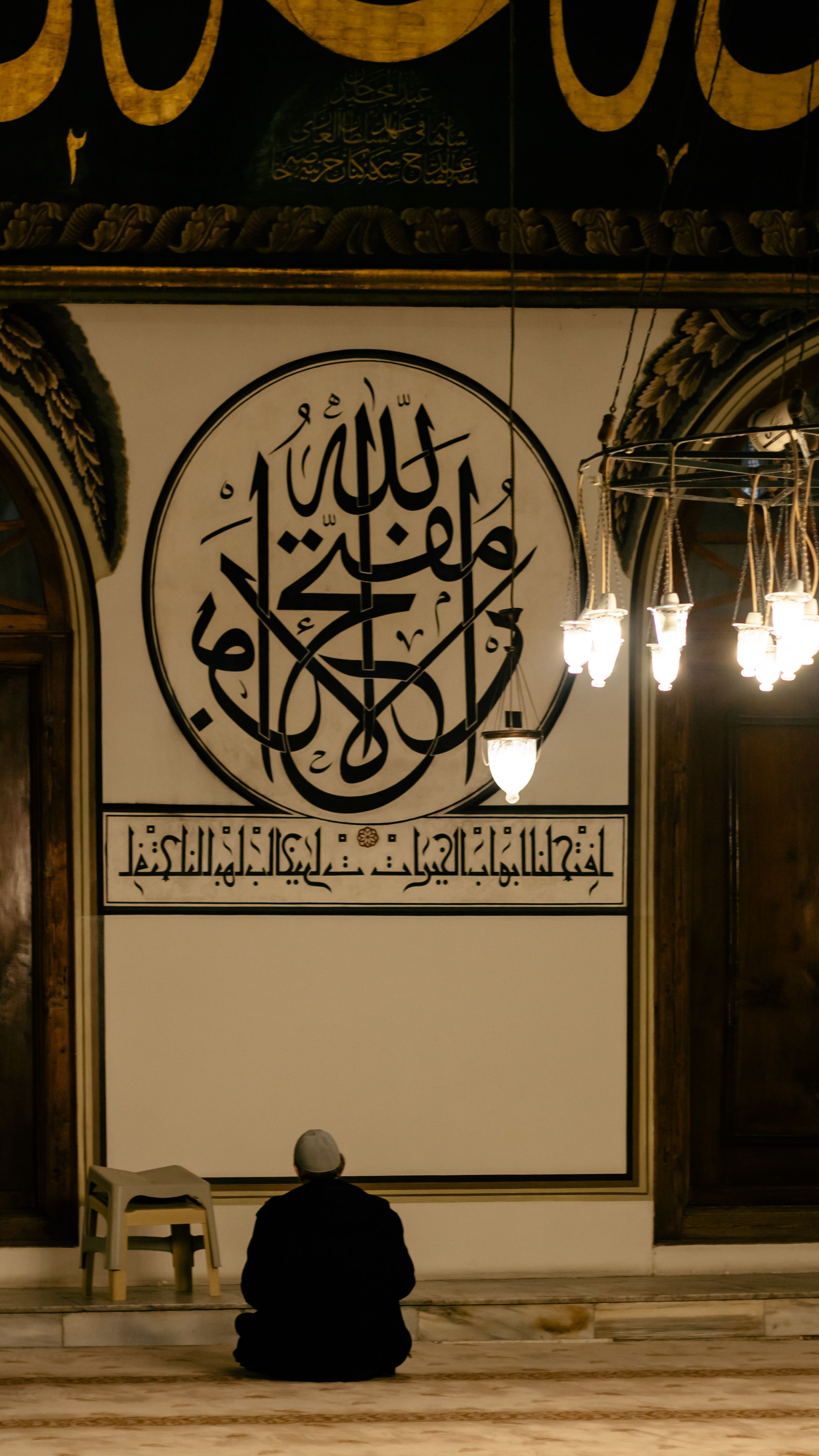Man in prayer inside Bursa Grand Mosque, Türkiye, showcasing Islamic art and architecture.