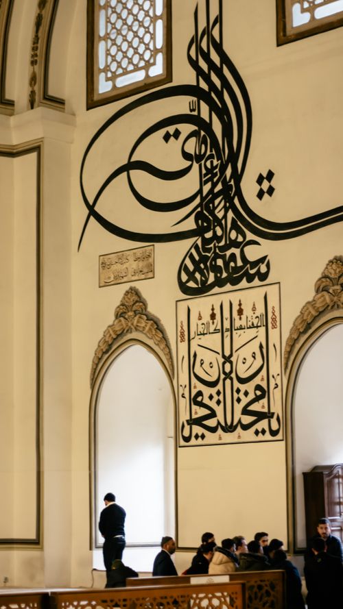 Free Worshippers gathered inside Bursa Mosque, Türkiye, with intricate Islamic calligraphy adorning the walls. Stock Photo