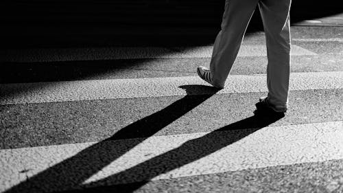 A person walking across a crosswalk in black and white