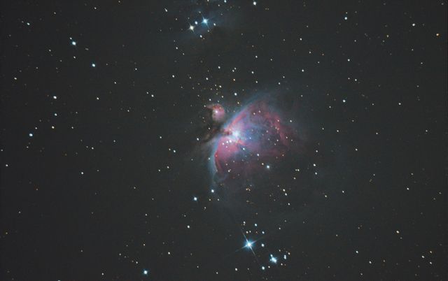 The Orion Nebula glowing pink and blue in a field of stars