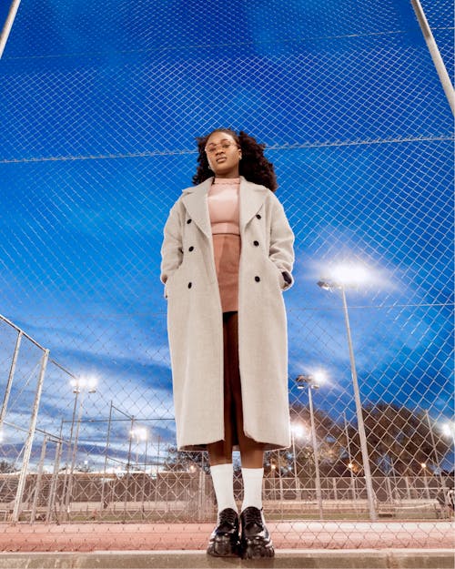 A woman in a coat standing on a baseball field
