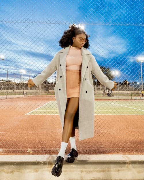 A woman in a skirt and coat standing on a tennis court